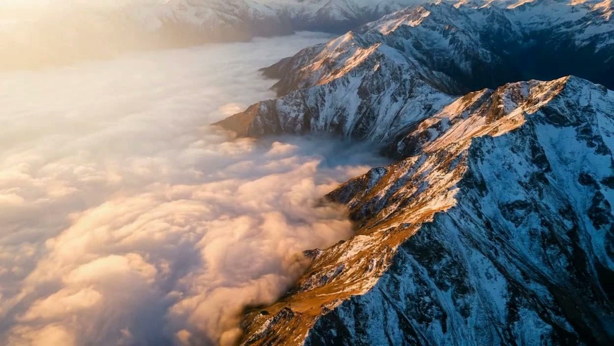 Finished cinematic aerial view across a mountain range at sunrise
